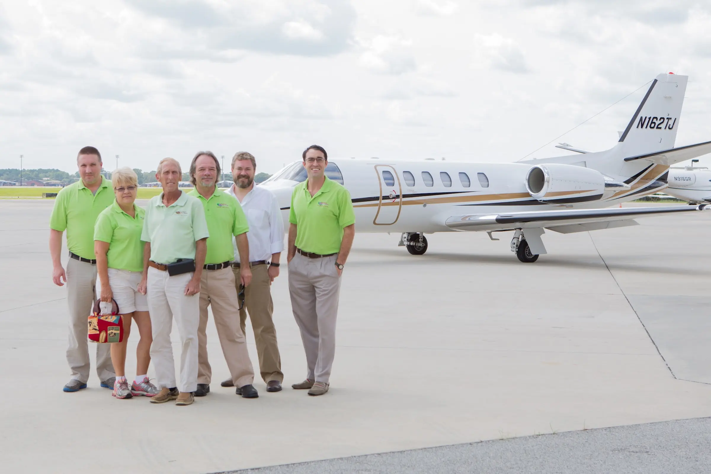 The Charleston Green Taxi team standing together on the tarmac in front of a private jet